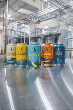 Image of Athletic Brewing Company's five flagship non-alcoholic beers in a brewery: Cerveza Atletica, Upside Dawn, Run Wild, Free Wave and All Out Stout